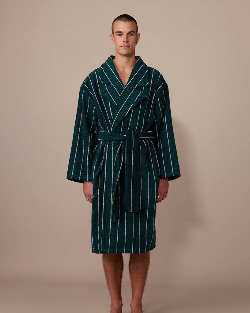 Man wearing a green striped robe against a beige background