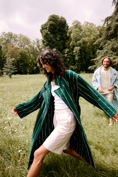 Woman in a Hommey Robe running through a grassy field with a man in the background.